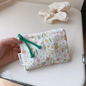 Floral cotton pouch detail showing small pink flowers and a woven green zipper puller