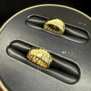 Close-up of dual golden croissant dome rings featuring unique wave ripple textures