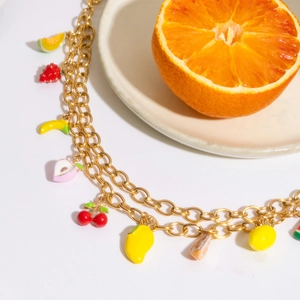 Macro detail of 18K gold plated chain with colorful enamel fruit charms and mini pearls