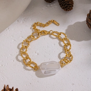 Dettaglio macro del bracciale a catena dorata con perla barocca e tag inciso S.STEEL