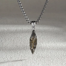Close-up of vintage rock texture triangular eye pendant with gold accents on metal chain