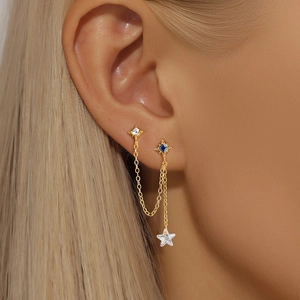 Detail view of gold double piercing earring with blue zircon and star pendant
