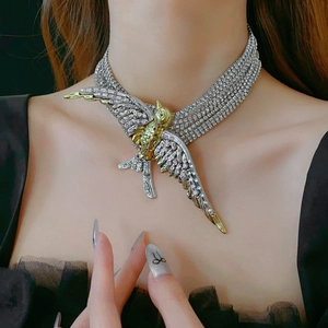 Close-up of golden swallow necklace with silver rhinestone inlay and layered metal design