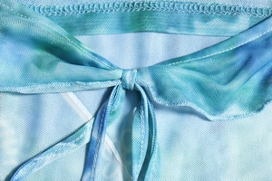 Detailed close-up of blue tie-dye mesh fabric with intricate knot and stitching details