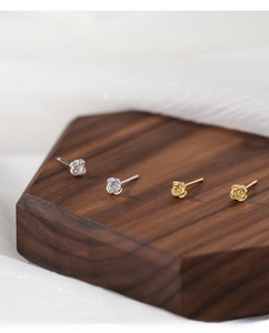 Detailed macro view of S999 silver and gold rose stud earrings on wooden stand