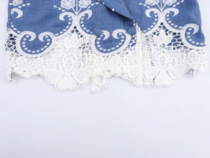 Close-up of blue jacket showing white floral embroidery and hollow lace trim detail