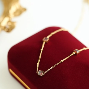Macro shot of 18K gold plated necklace with three square red zircons on velvet box