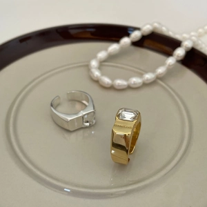 Chunky gold and silver Good Luck rings featuring a square clear zircon on a ceramic tray