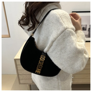 Detail view of black leather shoulder bag with gold metal letters and soft texture