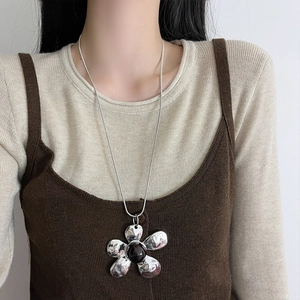 Retro silver flower pendant necklace with black center on a long snake chain