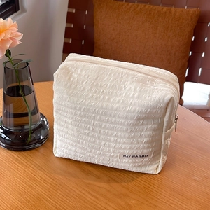 Gesteppte beige Canvas-Handtasche mit Reißverschluss und May Rabbit-Label auf Holztisch