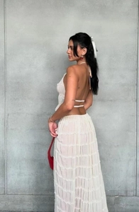Detail of white halter neck backless dress with tiered ruffles and elegant cut