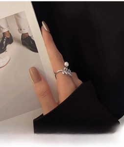 Dettaglio dell'anello a foglia con piccoli zirconi e una perla sulla mano della modella