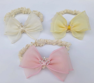 Three lace baby headbands featuring chiffon bows and rhinestone crown details in warm tones