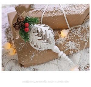 Detail of white hollow Christmas ball with green pine needles and red berries on faux snow