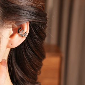 Close-up of a silver zircon-studded U-shaped double snake ear cuff on a model ear
