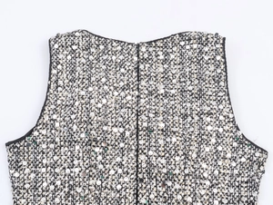 Detail view of shimmering silver sequins and black piping on a tweed sleeveless dress
