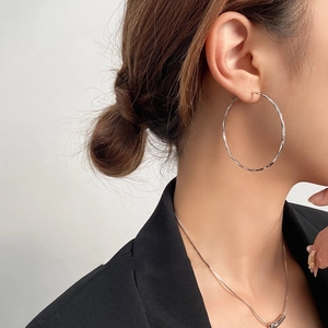Detail showing high-polish silver hoop earrings with subtle twisted texture on model