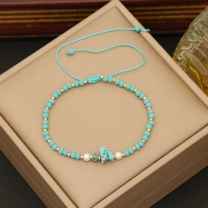 Bohemian woven bracelet with blue natural stones, pearls and beads on beige gift box