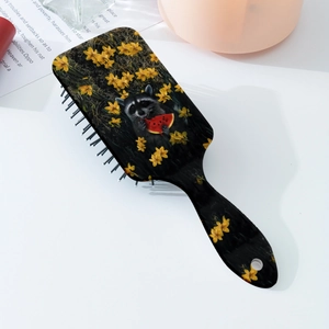 Detailed view of hairbrush with raccoon and floral print on a sleek black handle