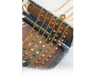 Detail of vintage gold star and moon necklaces with colorful enamel charms on a wooden box