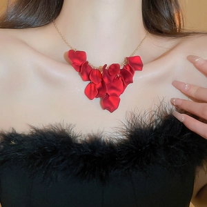 Close-up of red flower petal tassels on a gold-tone necklace worn by a model