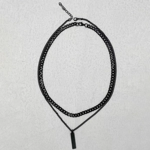 Close-up of double-layer black Cuban link necklace with rectangular pendant on white base