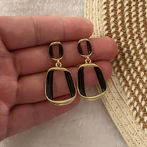 Fashionable gold-plated geometric earrings with black drip oil finish on hand