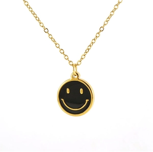 Détail d'un pendentif visage souriant en émail noir sur une chaîne dorée en acier inoxydable