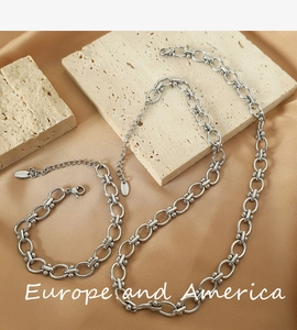 Detail of silver stainless steel chain jewelry set featuring oval links and metallic beads
