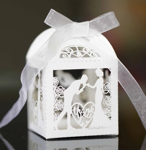 Close-up of white laser-cut wedding favor box with thank you message and silk ribbon