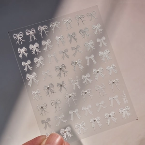 Macro detail of 3D embossed white bow nail art stickers with delicate pearl accents