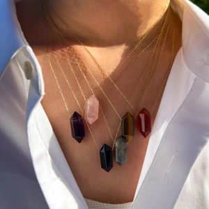 Stacked hexagonal double-pointed crystal pendant necklaces on model neck in various colors