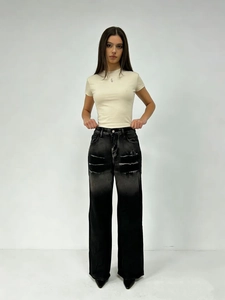 Detailed view of distressed black gradient wide-leg denim jeans with thigh rip design