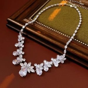 Macro shot of silver-tone teardrop zircon flower necklace on green velvet padding