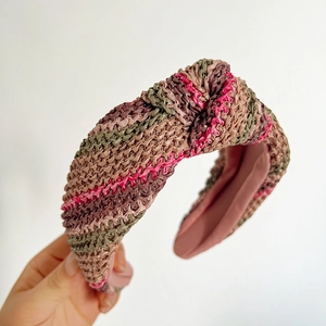 Détail d'un serre-tête large en paille tressée avec rayures colorées et nœud central