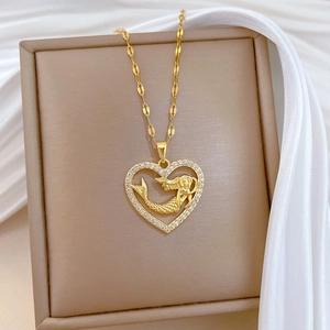 Luxurious gold mermaid heart necklace with sparkling crystals on a silk background
