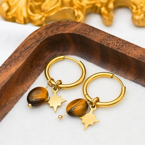 Macro shot of gold hoop earrings featuring natural tiger eye beads and star charms