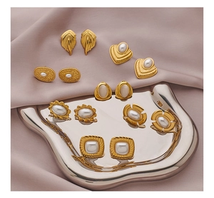 Detailed shot of vintage gold earrings with pearls on a silver tray and silk fabric