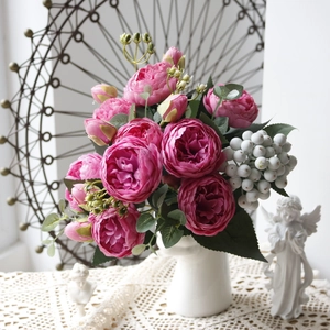 Detail of artificial pink peonies and white berries in a white vase for home decor
