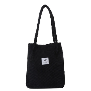 Classic black textured fabric tote bag with shoulder straps and a central white graphic label
