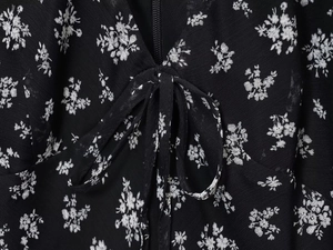 Detail van de bloemige zwarte chiffon jurk met blinde rits en strikhals detail