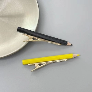 Détail de pinces à cheveux crayon créatives en noir et jaune avec clips bec de canard dorés