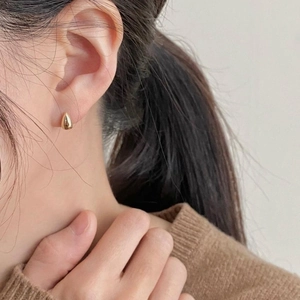Elegant 925 sterling silver gold teardrop stud earrings worn on model's ear