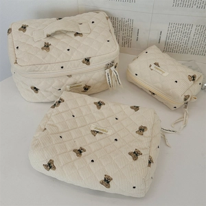 Detail of cream quilted bear print corduroy organizer bags with ribbon zipper pulls