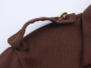 Detail of dark brown utility dress shoulder strap with a polished gold metal button
