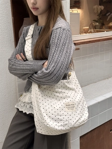 White canvas tote bag with black polka dots and pink star print in a lifestyle setting