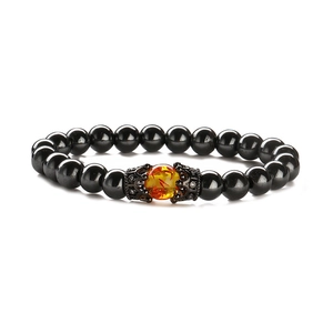 Detailed macro view of black glossy beads and amber-like bead with crown metal caps
