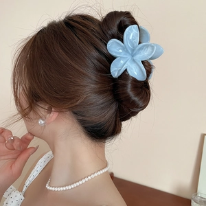 Vue détaillée de la pince à cheveux fleur en acrylique bleu marbré sur un chignon