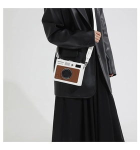 Detail view of the vintage camera-style crossbody bag in white and brown with shoulder strap
